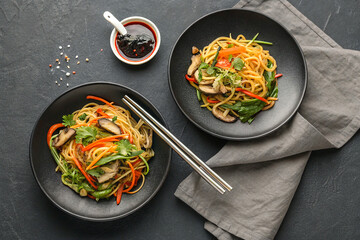 A top-down view captures two black plates, each filled with a vibrant, colorful assortment of fresh, beautifully arranged food.
