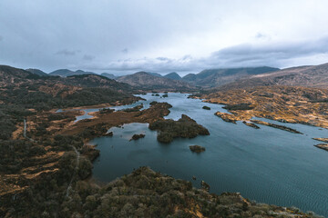 Aerial view of the tranquil Upper Lake Killarney reflecting the moody sky amidst rugged,...