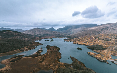 Aerial view of the tranquil Upper Lake Killarney reflecting the moody sky, surrounded by rugged...