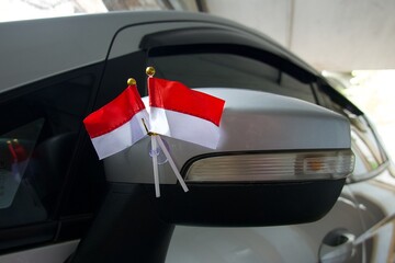 A pair of small, crossed red and white national flags mounted on a car window with a suction cup,...
