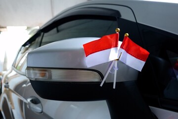 A patriotic display of two small Indonesian national flags attached with a suction cup inside a...
