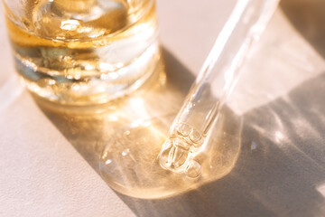 Close-up of a glass pipette with transparent gel with bubbles and colloidal gold. Cosmetic...