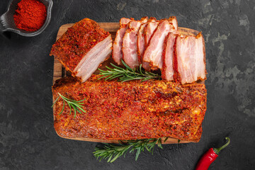 Sliced spicy pork belly coated in a rich red seasoning crust, garnished with fresh rosemary on a...