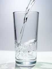 A stream of water flows into a transparent glass The water swirls at the bottom of the glass.