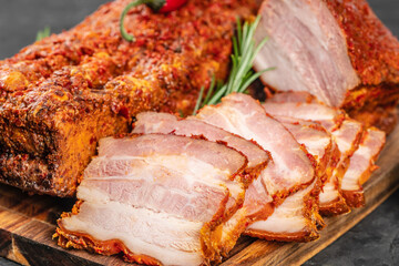 Close-up of juicy sliced pork belly with a spicy red crust, showcasing its marbled texture and rich seasoning on a rustic wooden board