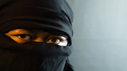 Close-up of masked male face lit by warm ambient light on black background, dramatic and secretive...