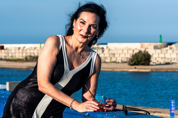 Elegant senior model enjoying cocktail by the sea