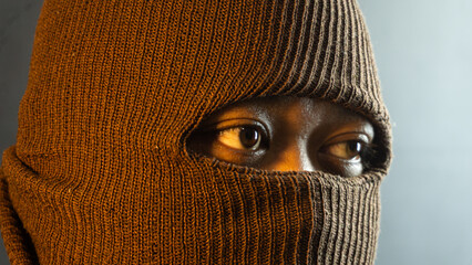Close-up portrait of male face with brown fabric mask and warm lighting, hidden identity theme with...