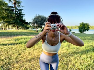 Cheerful woman taking pictures with digital camera and headphones
