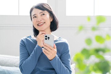 スマートフォンで調べ物をするミドル女性　ライフスタイルイメージ