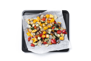 Roasted vegetables on a baking tray isolated on white on white background. Top view
