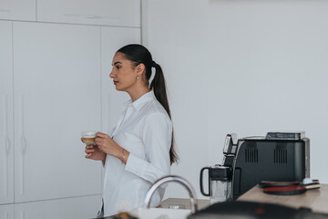Professional woman enjoying a coffee break in a sleek kitchen environment, reflected in her serene...