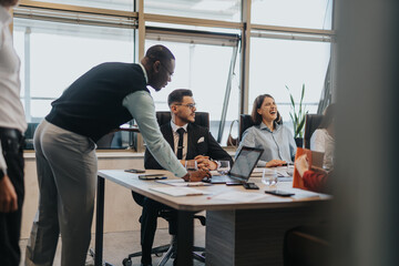 Diverse group of business people gathered in an office for a meeting. They're engaged in lively...