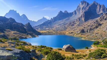 Obraz premium Scenic view of a lake surrounded by mountains and a clear sky