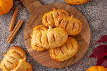 Pumpkin mini pies or hand pies with glass of coffee on a stone background. Traditional autumn dessert for Halloween and Thanksgiving. Copy space
