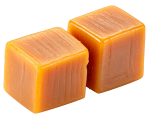 Caramel cubes sitting on clear surface, highlighting glossy appearance and golden brown coloration