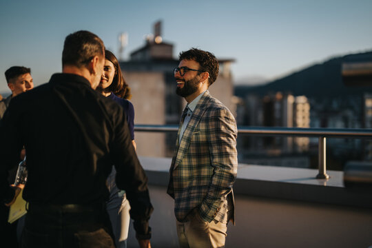 A diverse group of business colleagues engaging in a brainstorming session on a rooftop terrace during sunset, showcasing teamwork and collaboration.