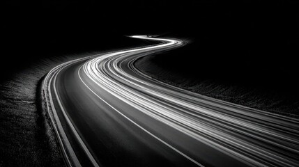 A captivating black-and-white photograph showcasing a winding road illuminated by dynamic light trails.