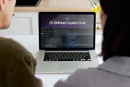 Programmers working with github copilot chat on laptop