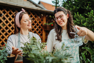 Two female friends or sisters taking care of plants with water can and mister	
