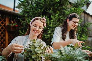 Two female friends or sisters taking care of plants with water can and mister	
