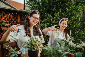 Two female friends or sisters taking care of plants with water can and mister	
