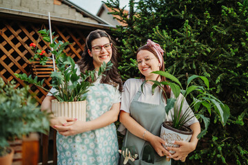 Two female friends or sisters taking care of plants with water can and mister	
