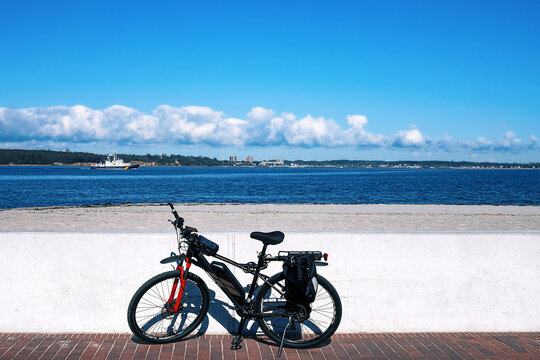 An e-bike stands against a wall on the beach of the Kiel Fjord.