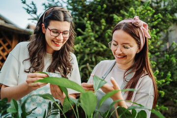 Two female friends or sisters taking care of plants with water can and mister	
