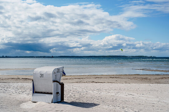 A single white beach chair stands on a beach in the Kiel Fjord in Germany.