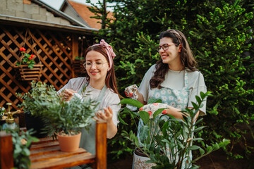 Two female friends or sisters taking care of plants with water can and mister	
