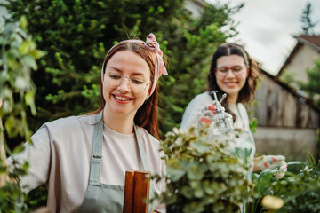 Two female friends or sisters taking care of plants with water can and mister	
