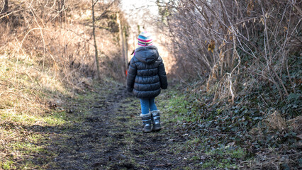 Young girl walking on a path in winter forest