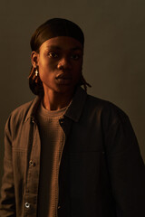 Portrait of young adult Black man wearing headscarf and earring looking directly at camera with...