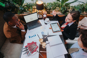 A group of diverse business people collaborating in a modern setting, analyzing data on laptops and...