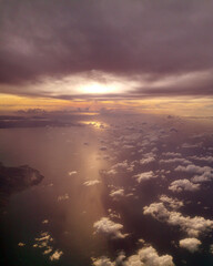 Aerial view of a serene ocean landscape at sunset, with dramatic clouds reflecting golden light...