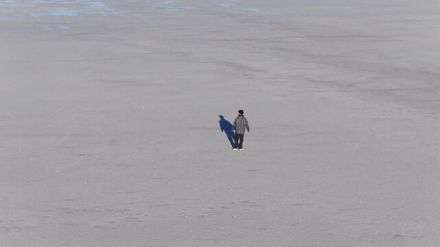 Aerial drone view captures minimalistic scene of man alone in surreal salt desert, isolation, exploration, self-reflection
