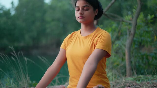 women in padmasana pose with closed eyes on a yoga mat at outdoor.