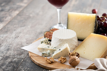 Board of different cheeses with nuts, figs, grapes and wine on wooden table. Copy space
