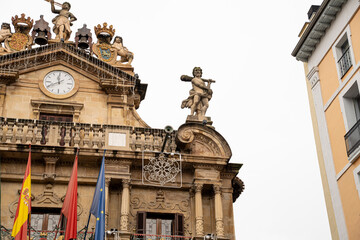 Historic city hall of Pamplona, Navarra features clock tower and statue on a cloudy day