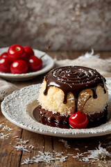 Kozacka Šapka, Traditional Croatian Sponge Cake with Chocolate Glaze and Coconut, decorated with cherry, Cossack Hat dessert. Unusual dessert recipe. Croatian culture. Croatian kitchen and food