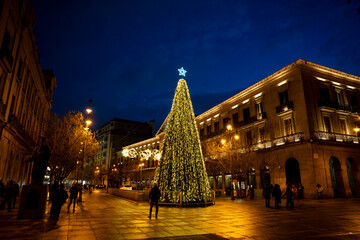 Festive Christmas tree lights up Pamplona square during evening celebration in Navarra, Spain