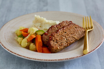 glazed meatloaf and mashed potatoes served with steamed vegetables