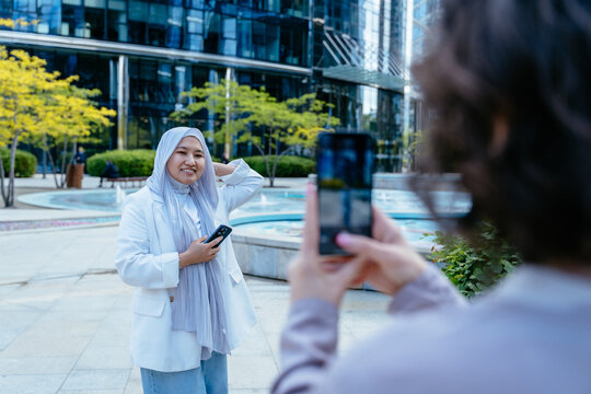 Woman posing for smartphone photo near fountain in city