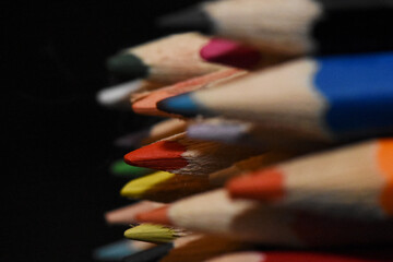 A vibrant macro photograph showcasing a stack of colorful wooden pencils against a dramatic dark...