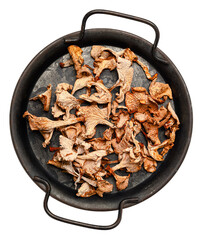 Dried gourmet wild forest mushrooms including chanterelles and porcini in a round black pan on a...