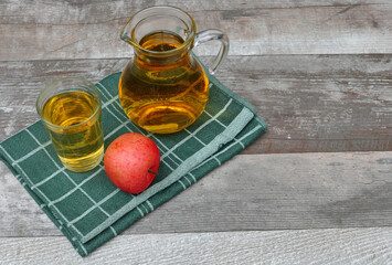 A jug of apple juice on a wooden board with space for text.