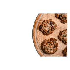 Homemade oatmeal cookies with nuts and dried fruits on a round wooden tray, isolated on transparent...