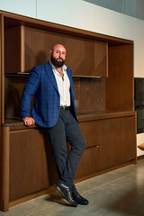 A stylish bearded man in a business suit in an interior