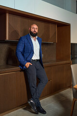 A stylish bearded man in a business suit in an interior